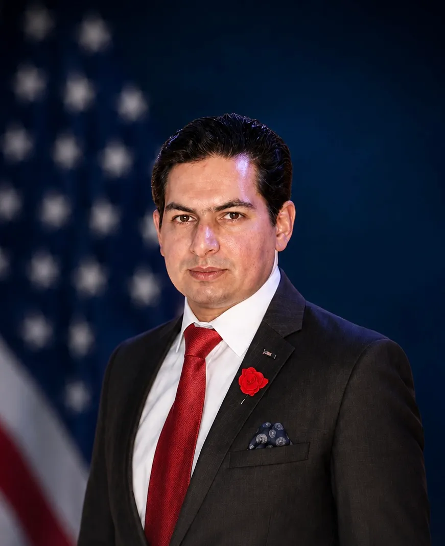 Qasim Lodhi in a charcoal suit and red tie with a rose lapel pin